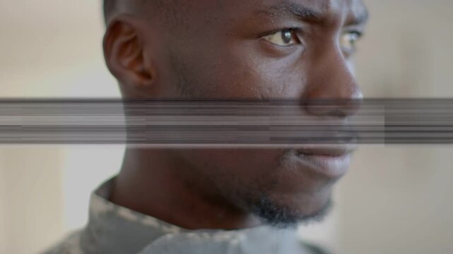 Man in military top biting lip and tracking off-camera sound, scan-line glitches crossing face