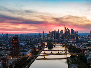 Naklejka premium Frankfurt skyline glowing over main river at sunset