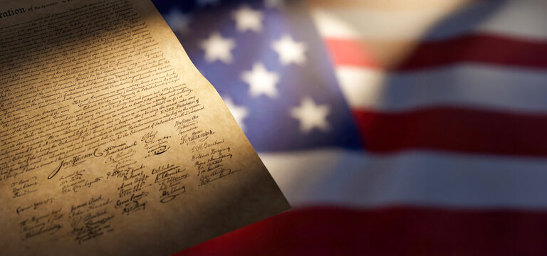 A document with many signatures rests near a flag of the United States. The signatures belong to key figures who helped shape the nation's history. This scene highlights American heritage