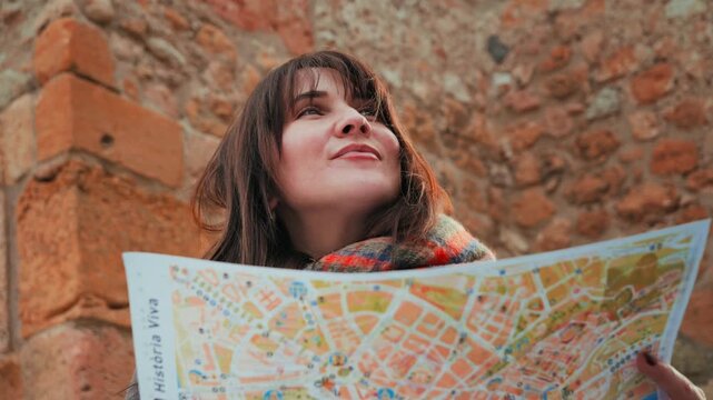 A girl with a paper map in her hands explores a new city and landmarks. A tourist looks at a map and plans her route through the city. High quality 4k footage