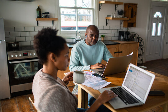 Couple managing home finances with laptops in kitchen