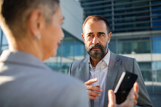 Business executive speaking with colleague outside modern office