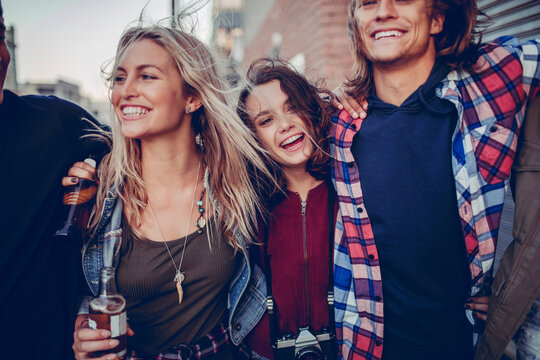 Young friends laughing with drinks on city street
