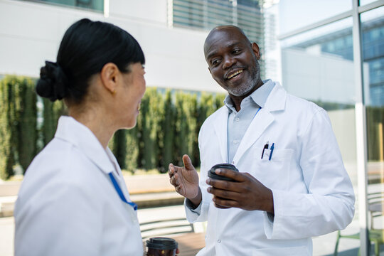 Two doctors talking over coffee outside hospital