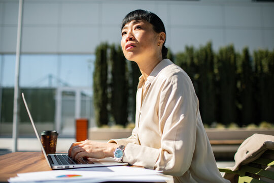 Professional woman working on laptop in outdoor office courtyard