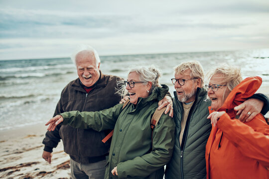 Group of senior friends laughing on a windy beach
