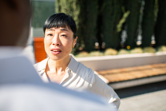 Concerned woman talking with colleague in office courtyard