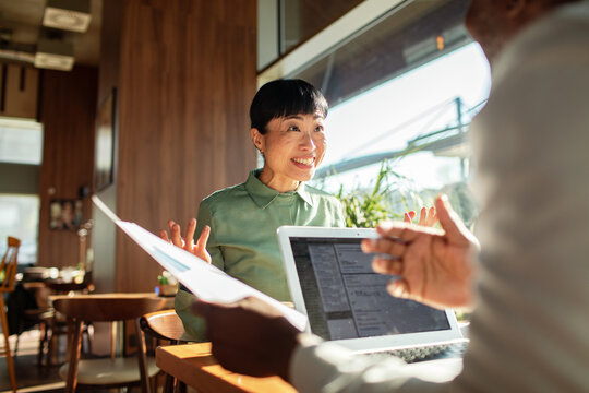 Coworkers discussing project with laptop in cafe