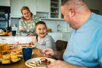 Fototapeta premium Smiling family enjoying breakfast together in home kitchen
