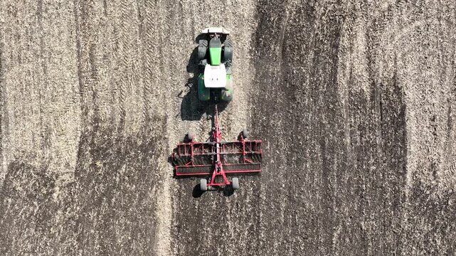 birds view of modern tractor working with disc harrow on the field with corn residue