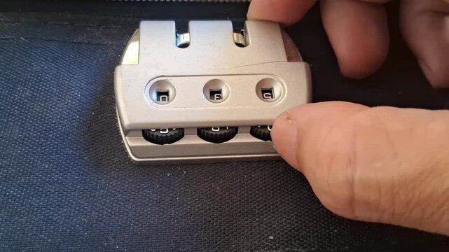 Fingers adjusting combination lock wheels on a bag in this close-up video footage