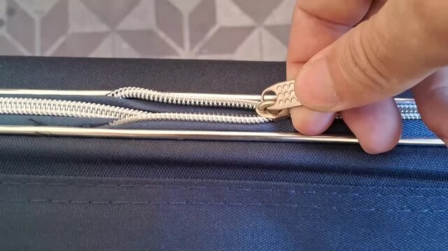 Person hand pulls metal slider to close luggage zipper in this smooth motion video clip animation