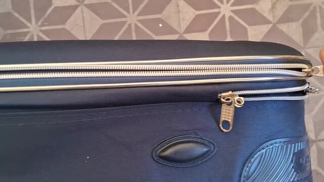 Hand sliding a metal zipper pull along a travel suitcase track in this smooth motion footage