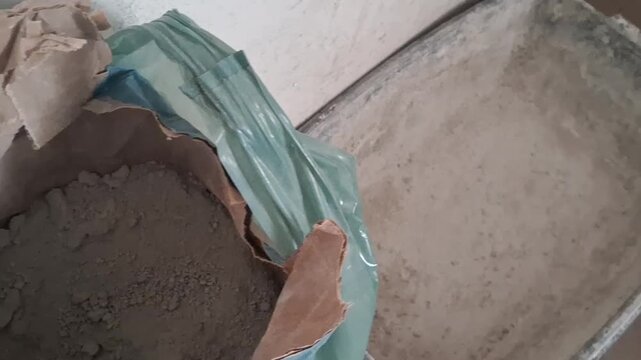 Pouring dry cement mix from a large bag into a construction trough, motion clip