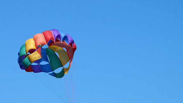 colorful parachute canopy against clear blue sky with radial lines and fabric panels