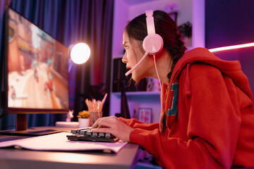 Host channel of young beautiful Asian gaming streamer, playing battle team gaming with multiplayer or single at warship on screen, wearing pastel color headset at digital neon light room. Stratagem. © InfiniteFlow