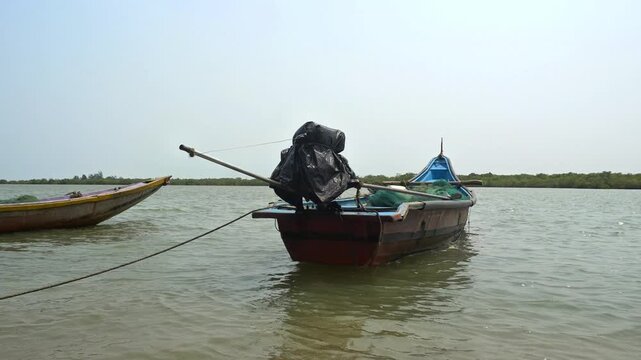 Motorized Traditional Indian Fishing Boat with Outboard Engine in Tropical Estuary. Traditional Wooden Boat with Fishing Gear and Net Moored at Sea Horizon. Rustic Working Boat for Fishing Industry.