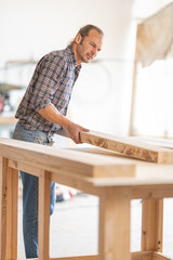 Fototapeta premium Carpenter working with wood plank in workshop