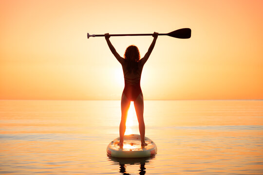 Young woman walking on stand up paddle sup boards by the sea during summer vacation
