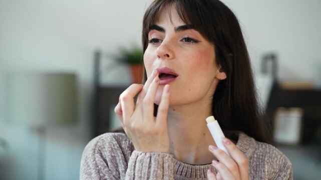 Video of pretty woman applying lip balm to her lips at home