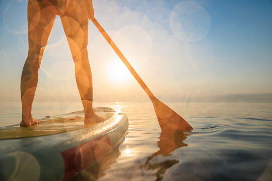 Women's legs on sup board by the sea during summer vacation