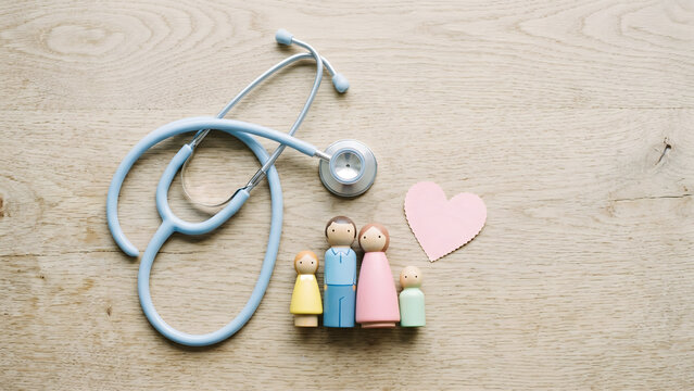 Stethoscope, wooden family figures, and heart symbolizing comprehensive healthcare and wellness for all ages