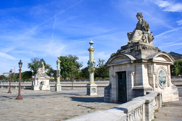 Fototapeta premium Ornate sculptures and classical architectural elements in central Paris. Elegant historic design with columns and stone structures under clear blue sky.