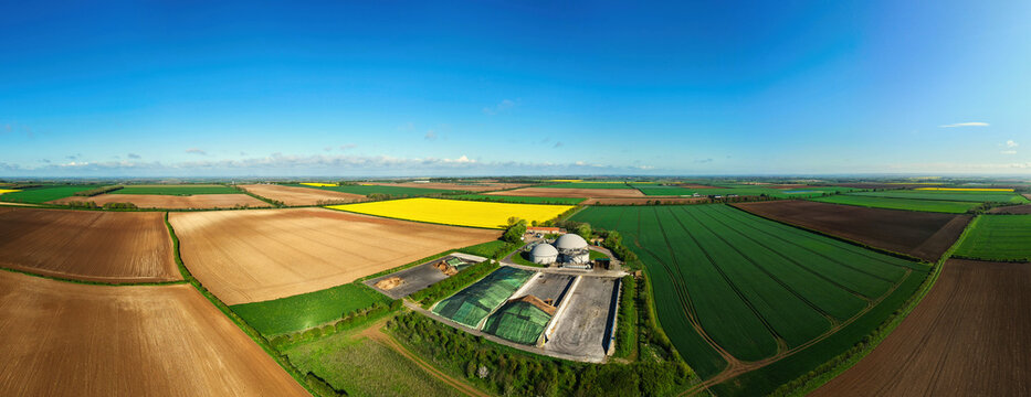 Aerial view of FBG Grange Farm Energy Spridlington biogas plant surrounded by vibrant yellow rapeseed fields and green agricultural land under a clear blue sky Market Rasen, England, United Kingdom.