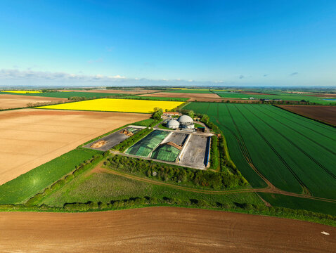 Aerial view of FBG Grange Farm Energy biogas plant with domed digesters and silage clamps surrounded by colorful agricultural fields in Market Rasen, England, United Kingdom.