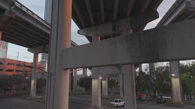 Underneath rows of concrete columns supporting three elevated expressway lanes and parking lot in the bottom