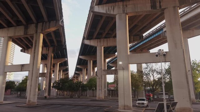 Underneath rows of concrete columns supporting three elevated expressway lanes and parking lot in the bottom