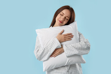 Fototapeta premium Beautiful woman with pillow on light blue background. Space for text