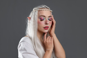 Fototapeta premium Beautiful girl dressed as elf on grey background