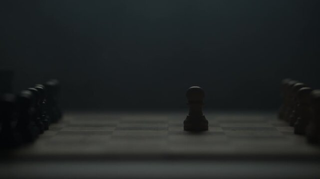 Cinematic close-up of a hand moving a chess piece in a dark atmospheric room. Low-key lighting highlights strategy, planning, and intellectual competition. Dramatic silhouette of a chess game.