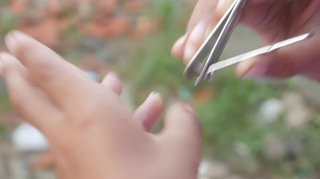a man is cutting his fingernails using a metal nail clipper