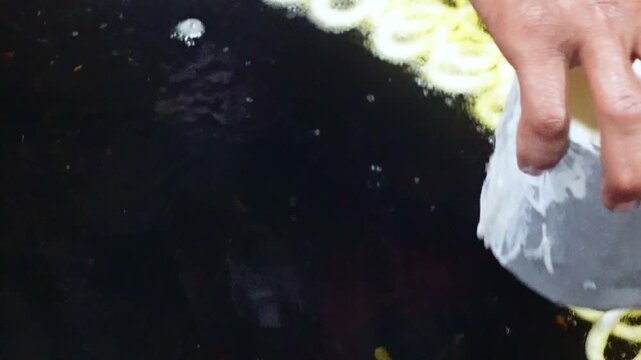 Sweet dessert food Jalebi is being fried in hot oil in an iron pan in a clay oven. Sweets maker making jalebis with his skillful hands.