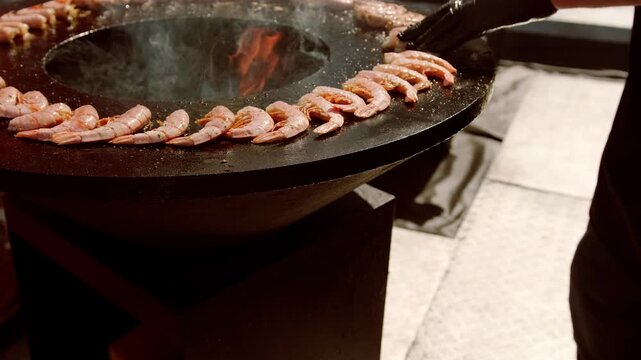 Shrimp cooking on outdoor charcoal circular grill. Seafood preparation on hot fire during street food festival. Culinary art and gourmet meal concept for dining event or party.