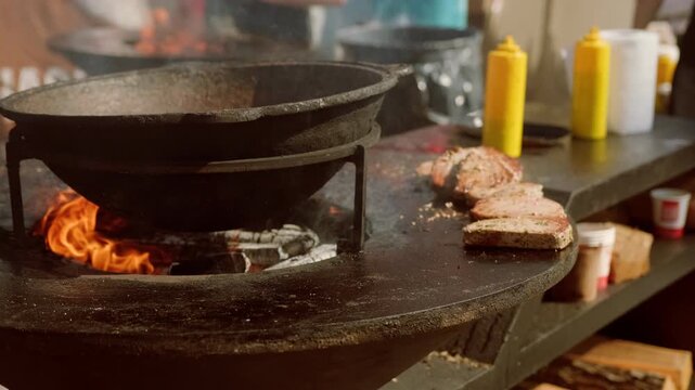 Small octopus cooking in large cast iron cauldron over open fire. Street food vendor preparing seafood snack. Traditional outdoor culinary process for festival and gastronomic event.