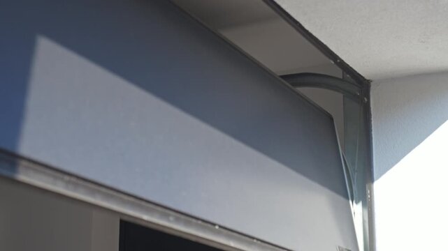 Sectional garage door closes along overhead metal track inside garage interior. Concept of home entry and property maintenance