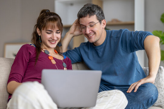 Couple enjoys time together while looking at a laptop in a cozy indoor setting during the day