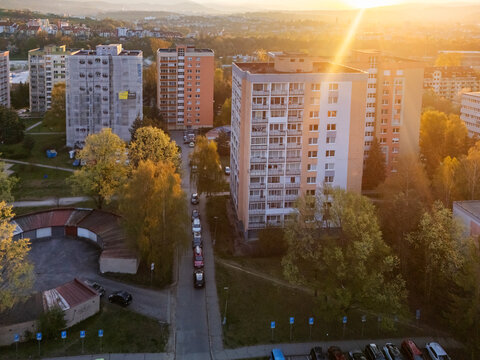 Aerial view of residential apartment blocks in the Spojova district during golden hour with warm sunlight and green trees in Banska Bystrica, Banskobystricky kraj, Slovakia.