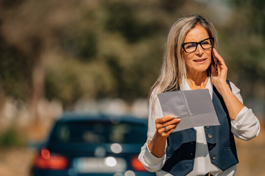 insurance concept_insured female driver or client with vehicle talking on cell phone with document, insurance
