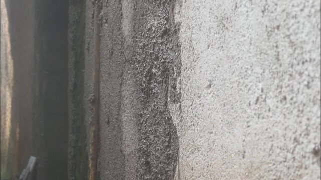 A construction worker is plastering a wall using a cement trowel on a house wall.