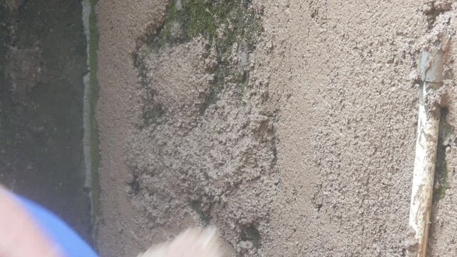 A construction worker is plastering a wall using a cement trowel on a house wall.