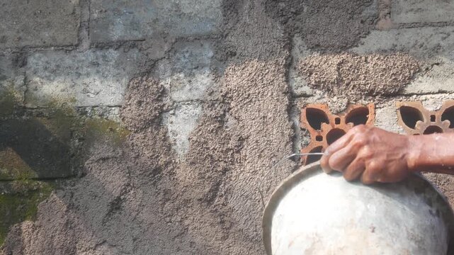 A construction worker is plastering a wall using a cement trowel on a house wall.