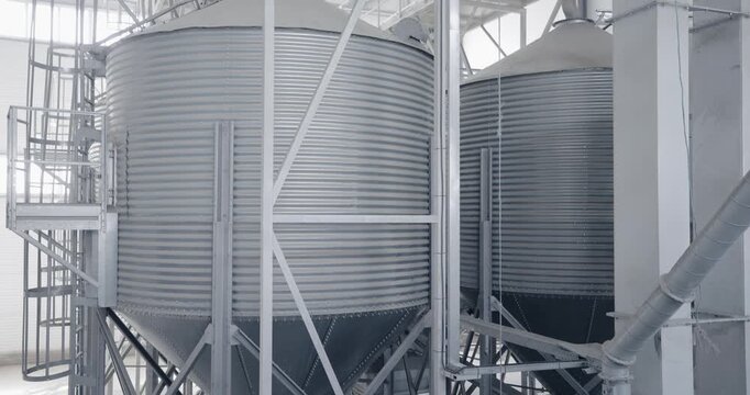 Modern industrial metal silos in agricultural facility interior, warehouse of grain.