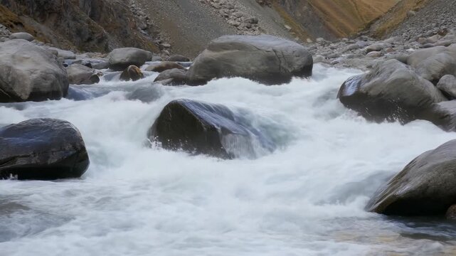 Flowing river water cascading over large rocks in a serene natural landscape. Represents the beauty and power of nature, ideal for relaxation and environmental themes