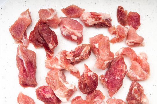 Raw meat pieces on a modern white cutting board with dotted textures