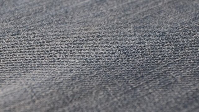 Smooth moving fold glides across blue denim fabric, revealing detailed texture and natural weave. Dynamic textile motion ideal for fashion, material, and background concepts.