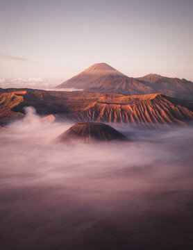 Aerial view of the volcanic peaks of Bromo Tengger Semeru National Park rising above a thick sea of mist during a soft sunrise Bromo, East Java, Indonesia.